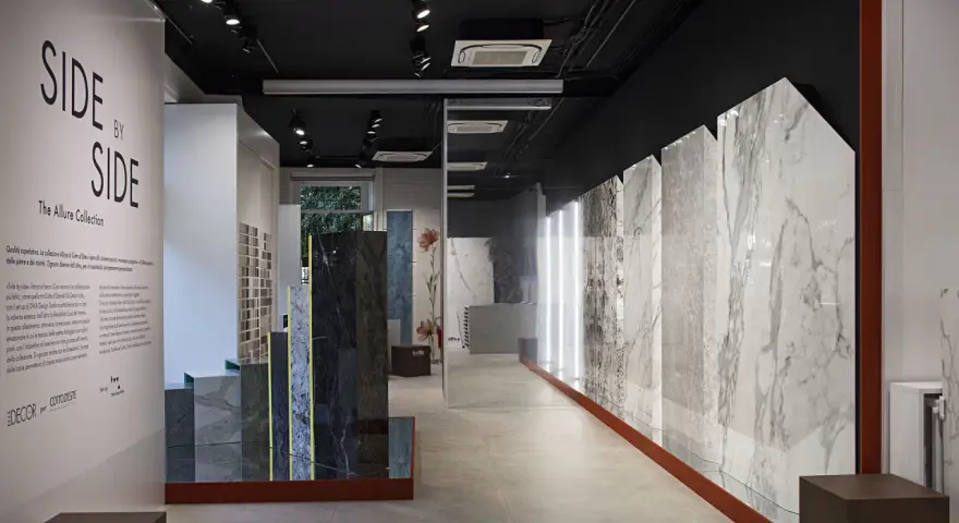 Interno showroom con lastre di marmo e design, esposizione "Side by Side" di Cotto d'Este, rivenditori di eccellenza.