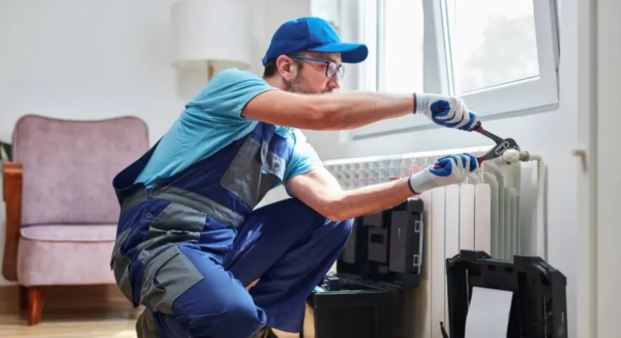 Tecnico con attrezzi lavora su termosifone. Scopri il lavaggio termosifoni in ghisa costo per un riscaldamento efficiente.