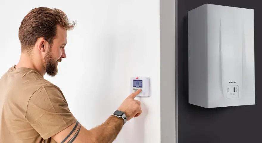 Uomo interagisce con termostato digitale, mostrando la differenza tra termostato e cronotermostato per ottimizzare il riscaldamento.