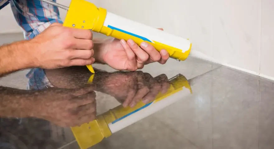 Applicazione di silicone con pistola per sigillare il box doccia.