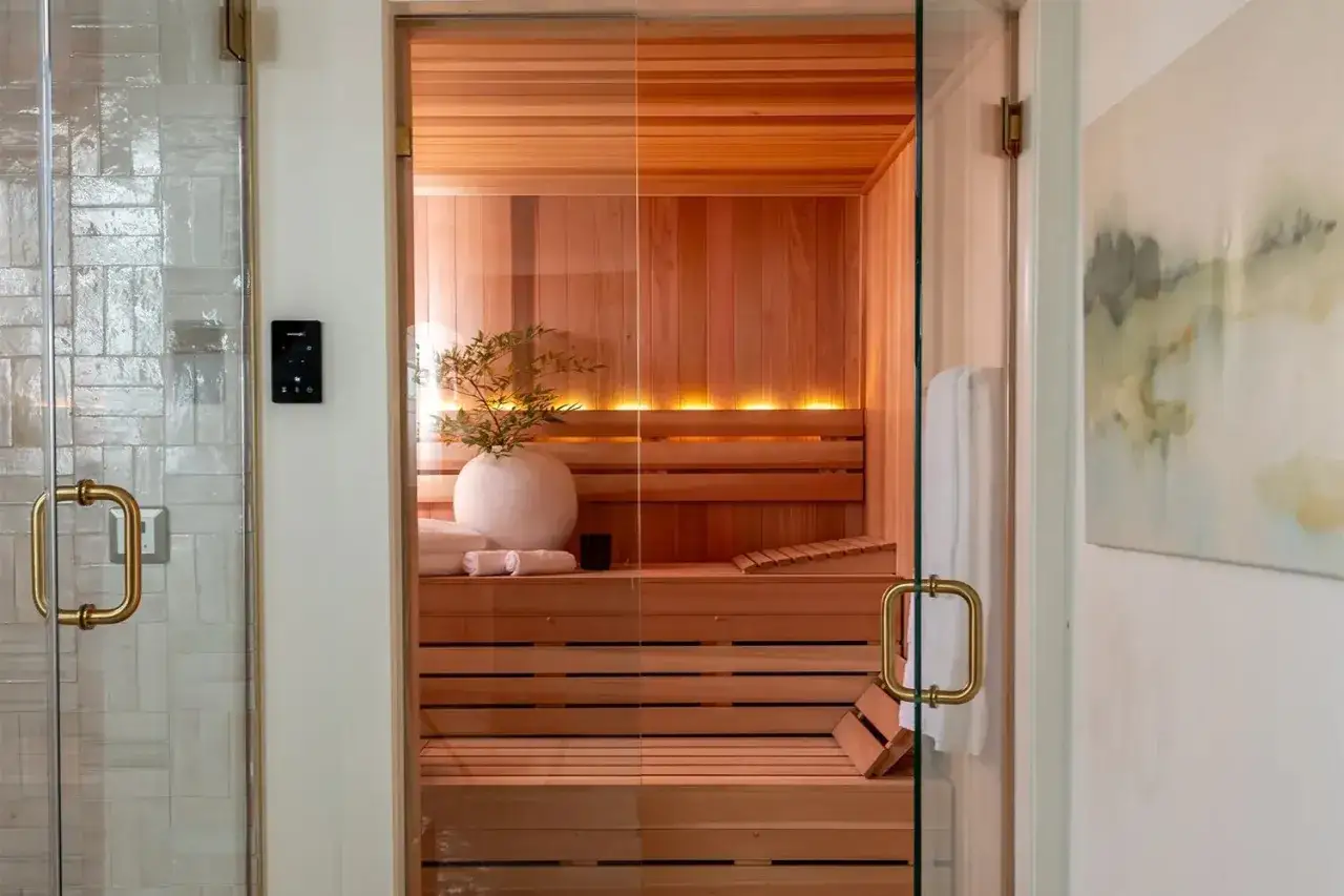 Interno di una sauna svedese in legno, con panche a pi&ugrave; livelli, illuminazione soffusa e un vaso decorativo.