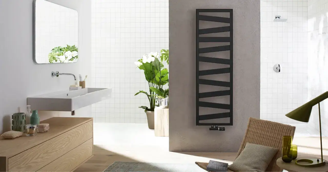 Un bagno moderno con lavabo sospeso, specchio, piante e un elegante termoarredo nero.