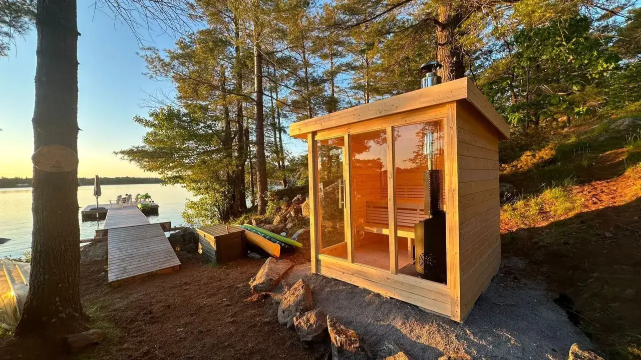 Una moderna sauna norvegese in legno con vetrate, affacciata su un lago tranquillo al tramonto. Perfetta per rilassarsi dopo una giornata all'aperto.