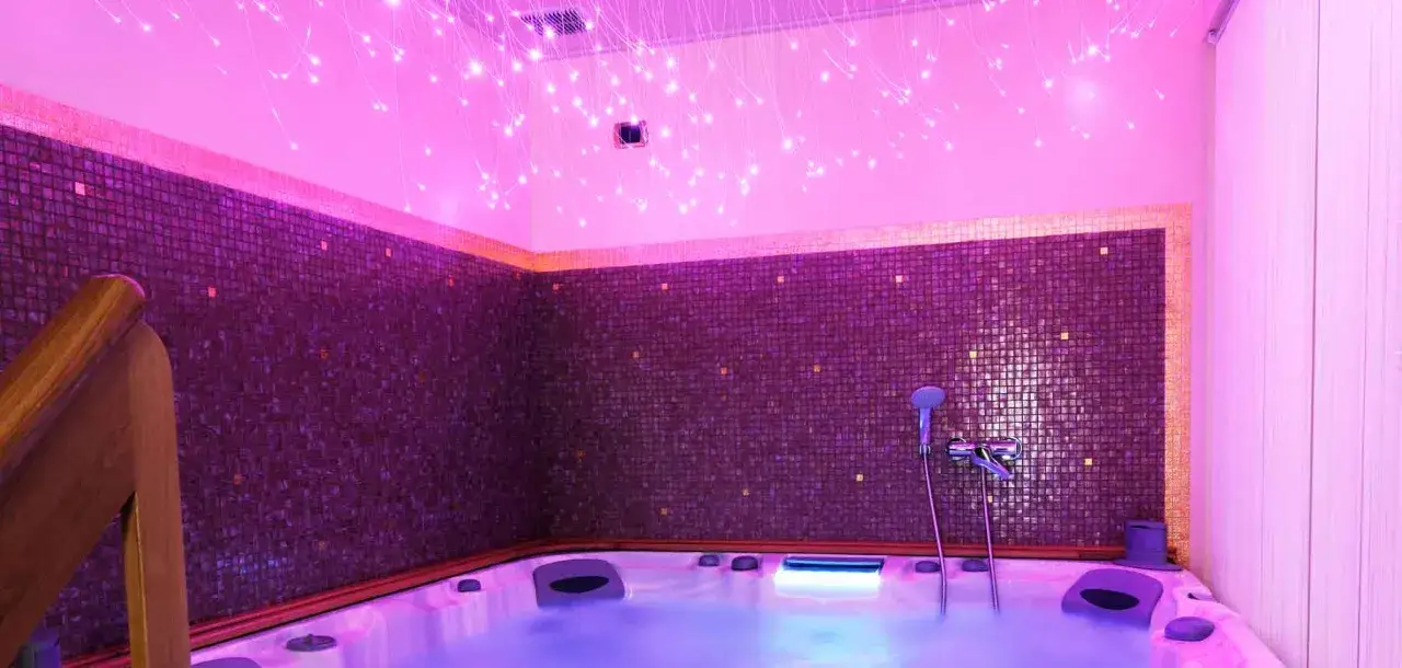 Un'oasi di relax con vasca idromassaggio e soffitto stellato. La cromoterapia spa avvolge l'ambiente in una luce rosa rilassante, creando un'atmosfera magica.