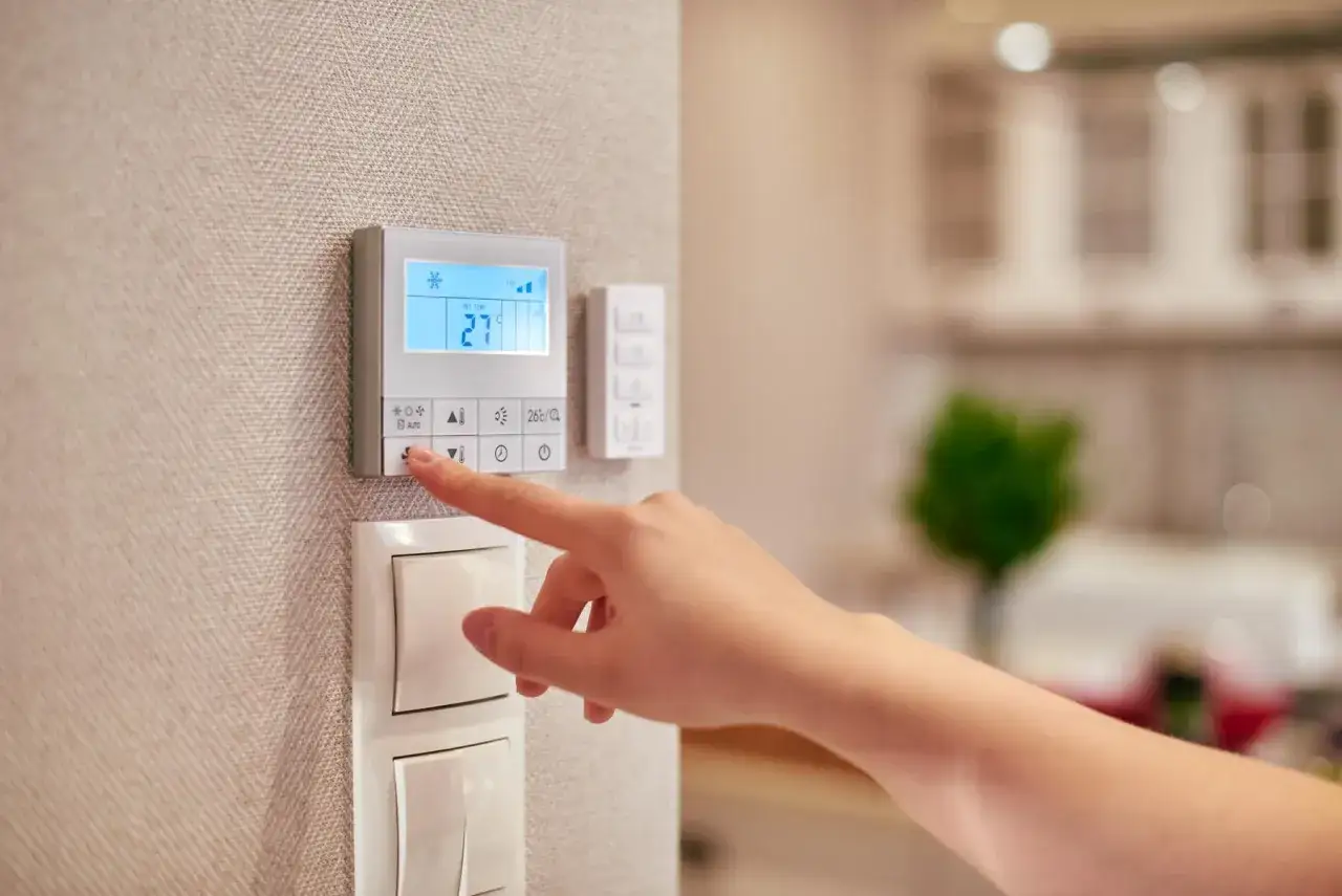 Mano che regola il termostato digitale, mostrando la differenza tra termostato e cronotermostato per un comfort personalizzato.