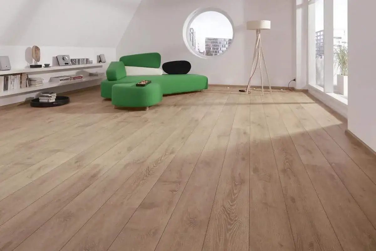 Un soggiorno moderno con un divano verde brillante e un pavimento in parquet essenze di legno chiaro, illuminato da una grande finestra.