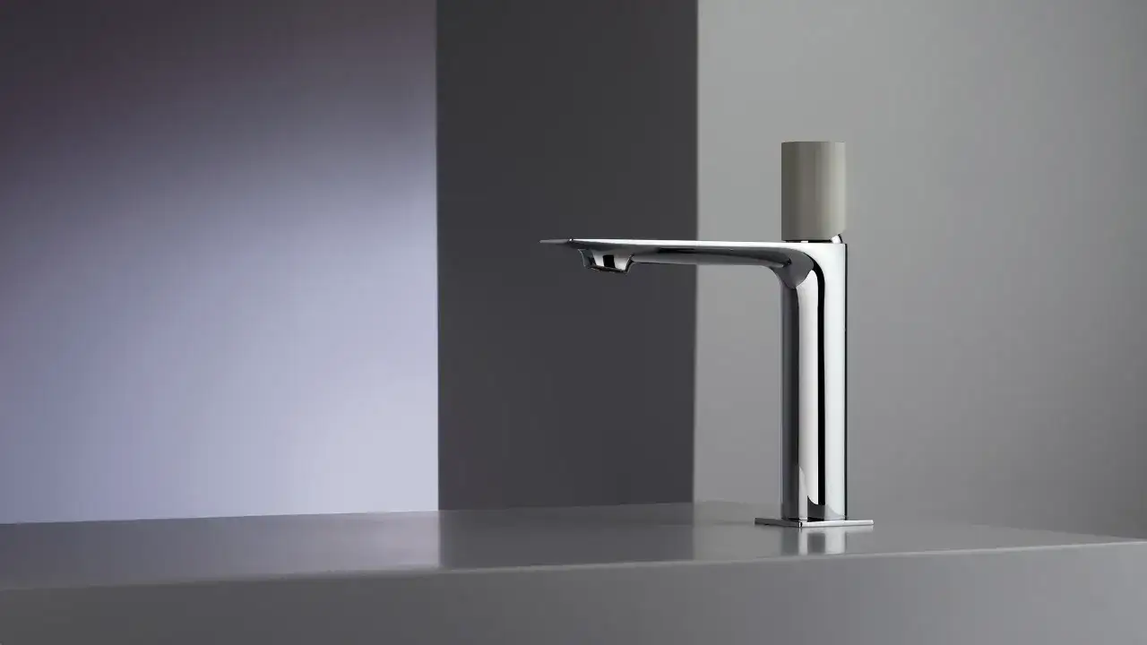Rubinetto di design Frattini, cromato con manopola grigia, su un piano d'appoggio minimalista.