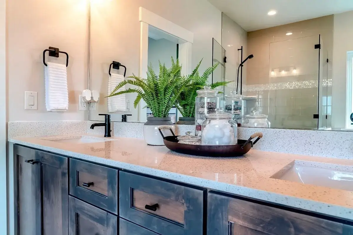 Un bagno moderno con doppio lavandino, rubinetti neri e un vassoio con cotone. L'altezza presa lavandino bagno è perfetta per l'uso quotidiano.