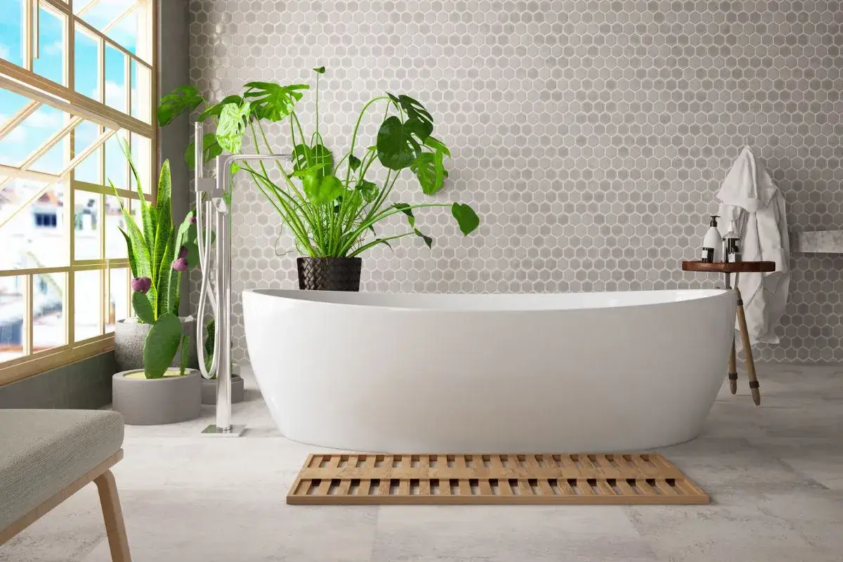 Vasca da bagno bianca freestanding, con rubinetto a colonna e piante verdi. Le misure della vasca da bagno sono ideali per un bagno moderno.