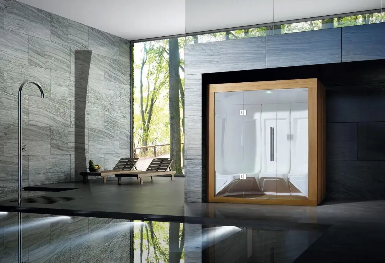 Moderno bagno dei turchi con cabina in legno e vetro, doccia a cascata e lettini prendisole affacciati sul verde.