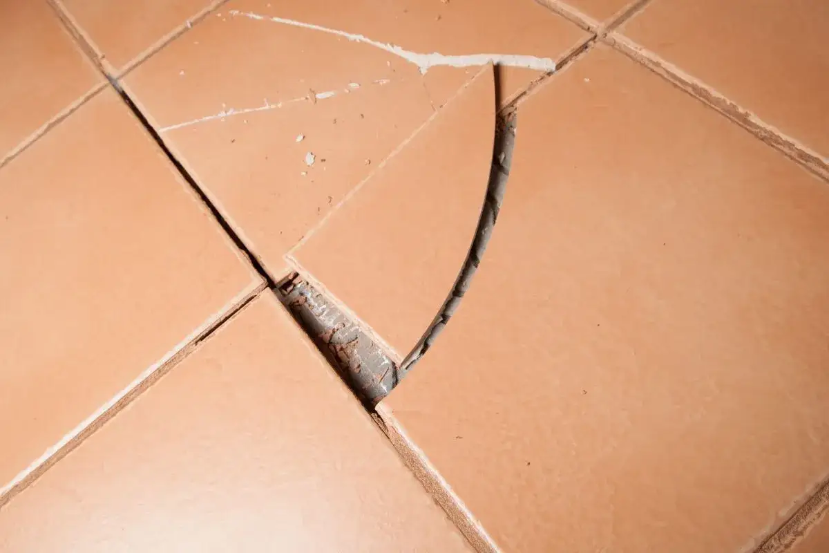 Piastrelle rotte mostrano quanto pavimenti si possono sovrapporre, rivelando il sottofondo.