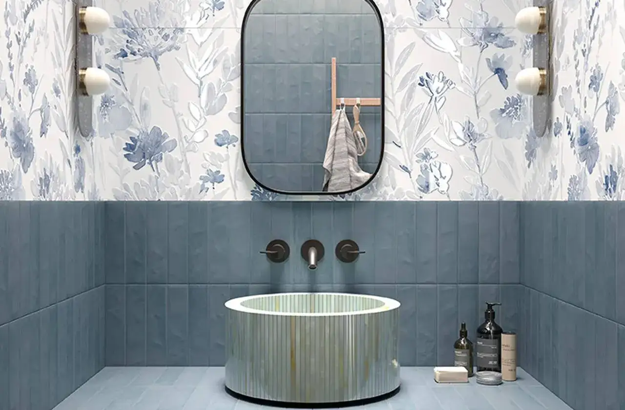 Bagno moderno con carta da parati floreale blu e bianco, pareti blu opache e un lavabo cilindrico. Il pavimento fap azzurro completa l'ambiente.