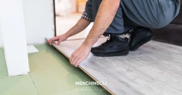 Installazione di un parquet flottante con finitura effetto legno chiaro. Un artigiano posa le tavole con cura.