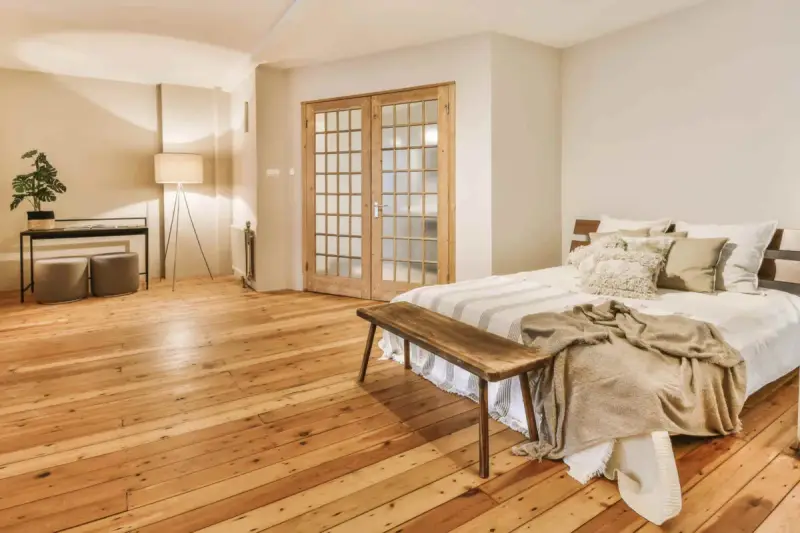 Camera mostra un letto, un armadio e un pavimento in legno. Il parquet è stato pulito con alcool, rendendolo brillante.