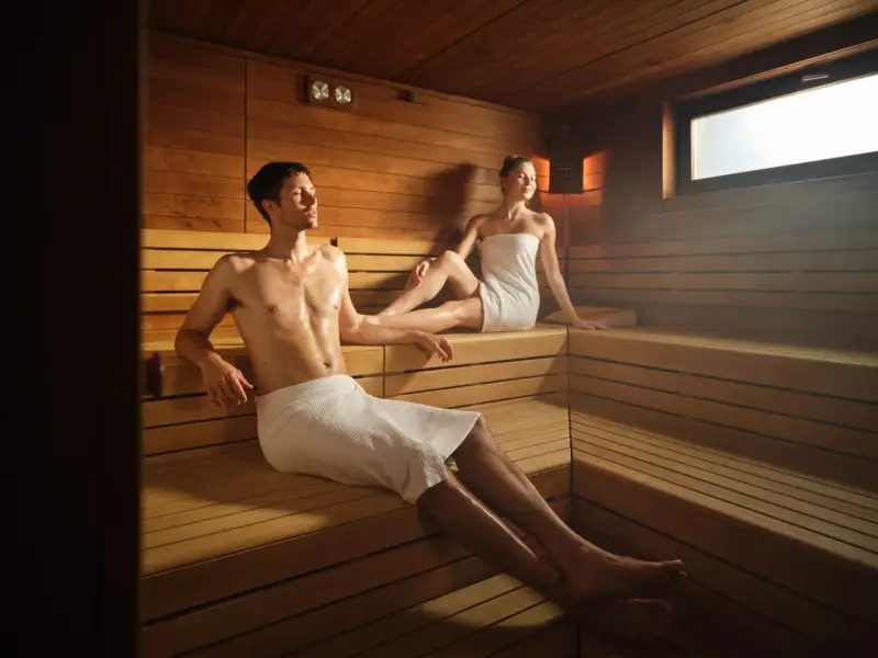 Coppia rilassata in sauna, un ambiente caldo e legnoso. Il calore aiuta a purificare il corpo, e molti credono che fare la sauna fa dimagrire.