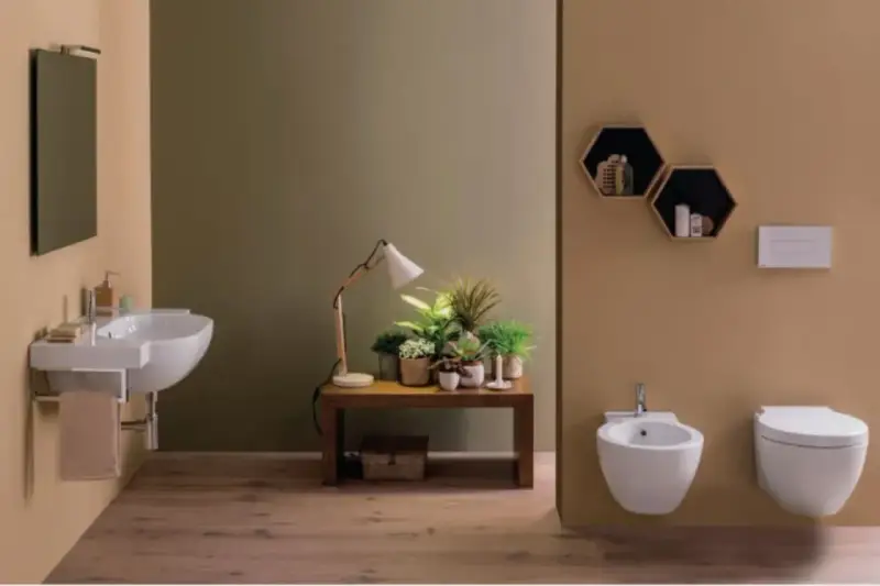 Bagno moderno con lavabo sospeso, bidet e vaso **ceramica globo**. Tavolino con piante e lampada.
